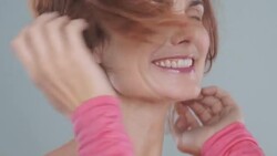Portrait of woman 40yrs + laughing and touching hair blowing in wind Stock Footage
