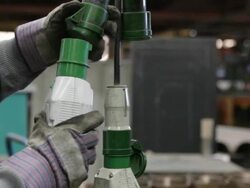 Caucasian factory worker's hands plug an industrial machine into a power source Stock Footage