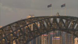 Australian flags wave on Sydney Harbour Bridge on a cloudy day. Stock Footage