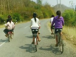 MS SLO MO Shot of group of girls riding bicycles on country road / Road from Luang Prabang to Nong Khio, Luang Prabang, Laos Stock Footage