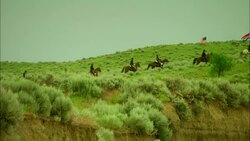 Soldiers of American 7th cavalry riding horses through countryside with regiment flag and Stars &amp; Stripes Stock Footage