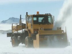 MS of snow plough working in icy landscape with mountains / Union Glacier, Heritage Range, Ellsworth Mountains, Antarctica  Stock Footage