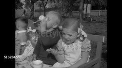 1937: NAZI GERMANY EDUCATION: Grade school children at long party table outside, swastika flags back of chairs, adults standing. WS Behind grade school boys in front of fence posters. CU Poster '4000 Jahre Krieg' (4000 years war). Boys reading posters Instructional Video