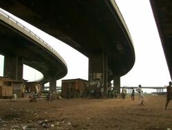WS View of people playing football in shanty village under road bridge / Lagos, Nigeria Stock Footage