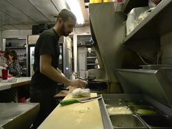 MS Cook cracking eggs into pan and waitress standing by register at classic American diner / Ann Arbor, Michigan, United States Stock Footage