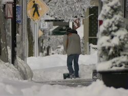 Man shoveling snow on small town city sidewalk Stock Footage