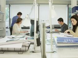 LA WS two men and two women working on  desk in modern office; one woman calls one of the men who walks around the desk to review some documents together with her Stock Footage