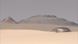 Conical rock formations jut above sand dunes in a remote desert area. Stock Footage