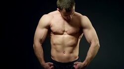 healthy athlete shows good muscle on black background Stock Footage