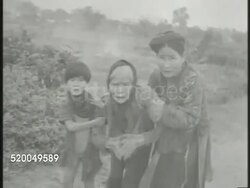 1946: CHINA: VS Various Chinese refugees walking through war torn town, collapsed buildings BG, family w/ emaciated elderly female walking, another elderly slouched on floor, naked toddler crying, elderly eating, baby eating vegetation. Suffering Instructional Video