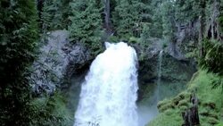 Man traverses highline stretched above waterfall, in forest Stock Footage