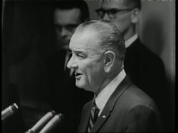 U.S. soldiers walk through the jungle in Vietnam as U.S. President Lyndon B. Johnson states, ...we will not surrender, and we will not retreat. News Clip