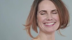 Portrait of woman 40yrs + laughing and touching hair blowing in wind Stock Footage