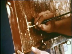 A man paints on wood. News Clip