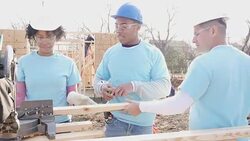Diverse group of volunteers work on home built for charity Stock Footage