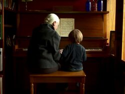 Camera pulls back slowly on grandmother and grandson playing piano. Stock Footage