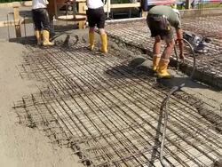 MS Shot of workmen working cement spreding on floor from cement bucket at construction site / Hermeskeil, Rhineland Palatinate, Germany Stock Footage