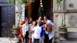 MS SWISH PAN Young boy taking multigenerational family portrait with smartphone and showing it to smiling family in front of restaurant entrance Stock Footage