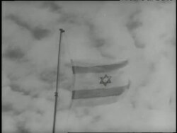 An Israeli flag ascends up a flagpole against a cloudy sky. News Clip