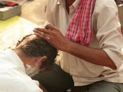Barber shaving head of a man, Haridwar, Uttarakhand, India Stock Footage