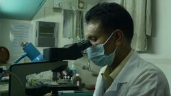 A technician examines a blood sample for evidence of infection by parasites on at a clinic operated on a hospital ship by a healthcare NGO in rural Bangladesh Stock Footage