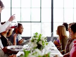 MS waitresses bringing food and wine to table of friends sitting at banquet table  Stock Footage