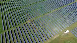 High Aerial Fly Looking Down at the Sun Reflecting off Solar Panel Arrays in a Huge Solar Power Plant Stock Footage