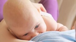 Mother breastfeeding her baby lying on back Stock Footage