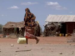 Woman rolls water canister in village Stock Footage
