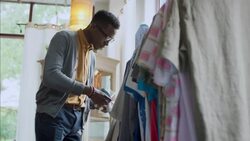 Young shop employee tags shirt in clothing store with tagging gun Stock Footage