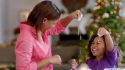 Mother and daughter laugh as they sprinkle flour on cookie dough in the kitchen (dolly-shot) Stock Footage