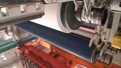 As a wheel spins a lever lowers on a machine in a paper mill. Stock Footage