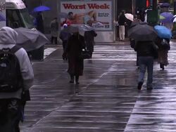Pedestrians carry umbrellas across an intersection on a rainy day in New York City. Stock Footage