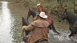 SLO MO DS Three horseback riders riding across river Stock Footage