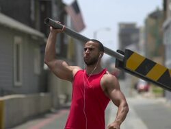 A man working out in an urban alley, doing shoulder press with a road barricade bar. - Slow Motion Stock Footage