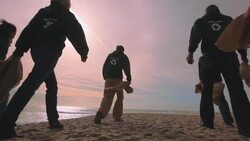 Volunteers walking past camera to shore Stock Footage