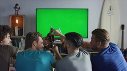 Guys sitting on couch watching tv and clinking bottles Stock Footage