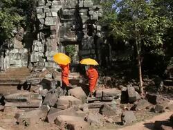 Cambodian monks walk through ruins at Angkor Stock Footage