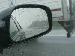 CU POV Shot of car mirror on highway in rain while passing truck / Missouri, United States Stock Footage