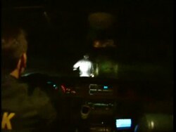 POV inside police car, chasing man through park, at night Stock Footage