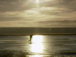 WS Shot of lone hockey player with stick handles skating on ice with shining sun / Arviat, Nunavut, Canada Stock Footage