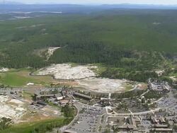 WS AERIAL View over cars parked near Old Faithful and dense forest / Wyoming, United States Stock Footage