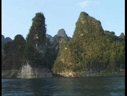 MS rocky shoreline and trees, view from water, Thailand Stock Footage