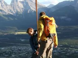 Two young climbers rappel (abseil) from mtn ridge Stock Footage