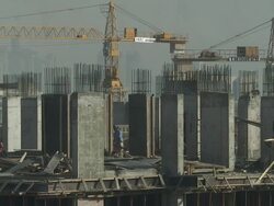 MS PAN Two yellow cranes sit in the middle of a high-rise construction site with Men work between the concrete columns / Doha, Qatar Stock Footage