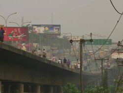 MS Shot of People and cars moving on bridge, electric wires with smoke / Lagos, Nigeria Stock Footage