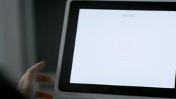 Customer writes signature with index finger on tablet touchscreen at checkout counter in local shop Stock Footage