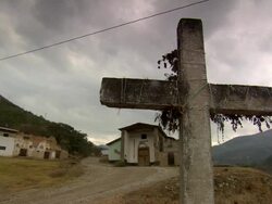"CU of stone cross, man pulling large leafed branches down gravel path, small church and villiage behind, mountain valley in b/g, rural Amazonas region of Peru [PerÃƒÂº]" Stock Footage