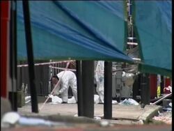 Police at scene of bus blast; body bags; flowers at nearby church News Clip