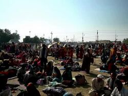 Campfire smoke drifts past as crowds of people in groups sit on ground, resting, organizing, very peaceful at the Kumbh Mela, India. Stock Footage